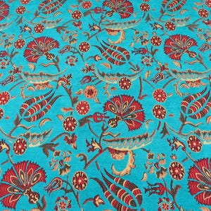May include: A turquoise fabric with a repeating floral pattern. The design features red and brown flowers, leaves, and stems. The flowers have a detailed, stylized appearance, and the overall effect is ornate and decorative.