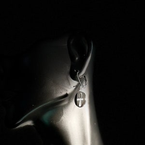 Op de afbeelding: Zilveren Ankh-oorhangers met een rond ontwerp. De oorbellen worden getoond aan het oor van een mannequin.