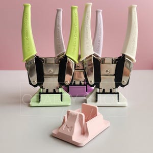Puede incluir: Cuatro herramientas de punzonado de esquina We R Memory Keepers en diferentes colores, incluyendo verde, morado, blanco y rosa claro. Las herramientas están etiquetadas con el nombre de la marca y "Crop-A-Dile Corner Chomper".