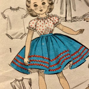 May include: A vintage sewing pattern illustration featuring a doll with brown hair and a red bow, wearing a white blouse with red polka dots and a blue skirt with two rows of red zigzag trim, accompanied by a white petticoat and additional garment sketches.
