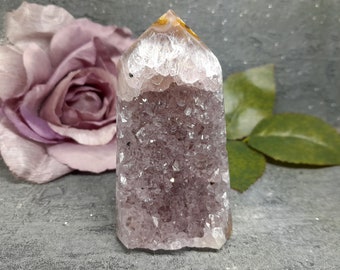 Peut inclure: Un cristal d'améthyste violet avec une formation naturelle de druse et un sommet clair et pointu. Le cristal a la forme d'une pointe et une texture naturelle et rugueuse.