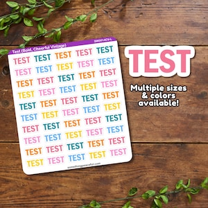May include: A sheet of colorful "TEST" stickers with a variety of colors and sizes. The sheet is on a wooden background with green plants.
