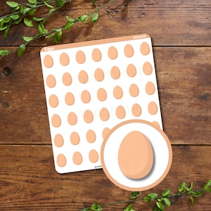 May include: A sheet of stickers featuring light brown egg illustrations. The word "Eggs" is printed at the top left corner. A close-up of a single egg is in a circle at the bottom right. The stickers are on a white background.