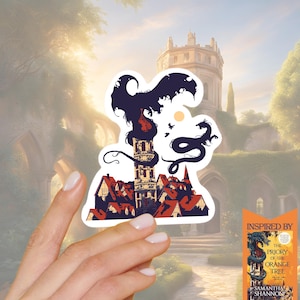 May include: A white sticker with a fantasy illustration of a tower, buildings, and dragons in black and red. The sticker is held in front of a blurred background of a castle and greenery. The sticker is inspired by "The Priory of the Orange Tree" by Samantha Shannon.