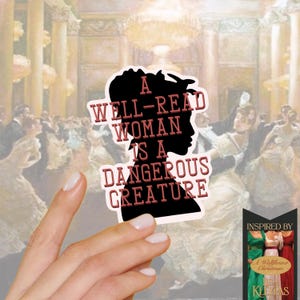 May include: A black sticker with the silhouette of a woman's head and the text "A WELL-READ WOMAN IS A DANGEROUS CREATURE" in red letters. The sticker is held in front of a painting of a ballroom scene. The sticker is inspired by "A Wallflower Christmas" by Lisa Kleypas.
