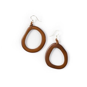 May include: A pair of brown leather earrings with a unique, organic shape. The earrings are made of a natural material and have a simple, elegant design.