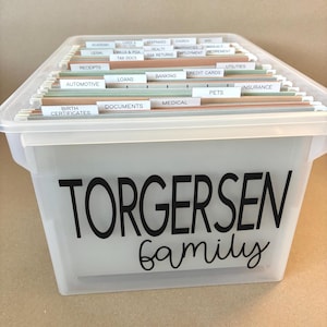 May include: A clear plastic storage bin with a black label that reads "Torgersen family". The bin is filled with hanging file folders labeled with various categories, including "Receipts", "Loans", "Banking", "Credit Cards", "Utilities", "Insurance", "Pets", "Medical", "Documents", "Birth Certificates", and "Automotive".