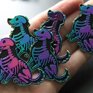 Könnte beinhalten: Fünf regenbogenfarbene Emaille-Pins mit einem Cartoon-Hundeskelett in verschiedenen Posen. Die Pins haben einen schwarzen Umriss.