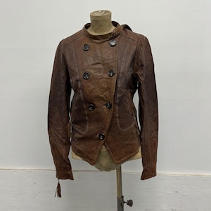 May include: A brown leather jacket featuring a double-breasted front with five dark buttons, a high collar with a small strap closure, long sleeves with zippered cuffs, and two side pockets with small leather tassel pulls on the zipper sliders.