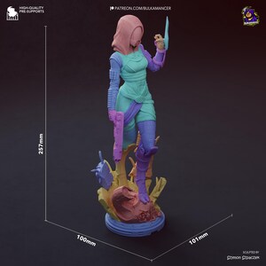 May include: A 3D-printed figurine of a female character in a futuristic outfit, holding a pistol and a blade. The figure is approximately 100mm x 101mm x 257mm and is mounted on a detailed base. The color scheme includes teal, purple, and pink.