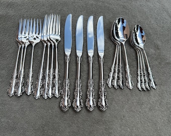 May include: A set of silverware with ornate handles, including forks, knives, and spoons. The silverware is made of polished stainless steel and has a silver finish.