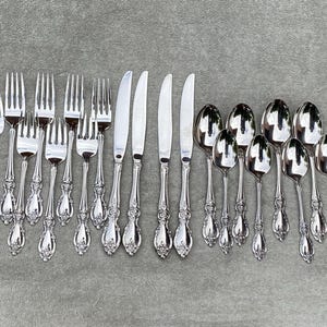 Könnte beinhalten: Ein Besteckset mit verzierten Griffen, bestehend aus Gabeln, Messern und Löffeln. Das Besteck ist aus poliertem Edelstahl und hat ein klassisches Design.