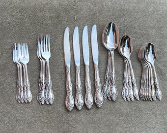 Könnte beinhalten: Ein Besteckset mit verzierten Griffen, bestehend aus Messern, Gabeln und Löffeln. Das Besteck ist aus poliertem Edelstahl und hat ein klassisches Design.