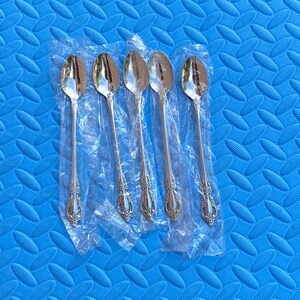 Peut inclure: Cinq cuillères argentées avec des manches ornés sont présentées dans un emballage plastique transparent. Les cuillères ont une surface réfléchissante et sont posées sur un fond bleu texturé. Les cuillères semblent neuves.