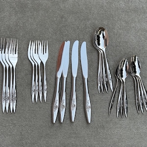 May include: A set of silverware with a floral design. The set includes forks, knives, and spoons.