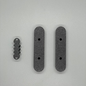 May include: Three black plastic pieces, two are long and rectangular with rounded ends and two holes, the other is a small, toothed piece with a hole.