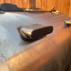 May include: Close-up of a silver smoker with a black handle and a small, rectangular, silver and black vent.