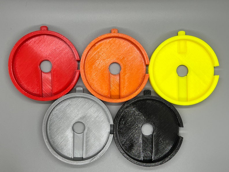 May include: Five 3D printed plastic discs in red, orange, yellow, silver, and black. Each disc has a hole in the centre and a slot cut out of the side.
