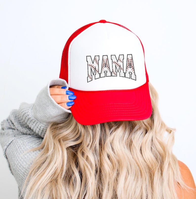 May include: A white and red trucker hat with a baseball-themed "MAMA" graphic. The hat has a mesh back and a curved brim.