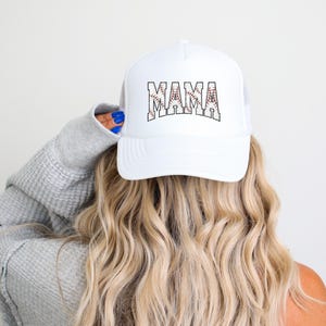 May include: White baseball cap with a black and red baseball graphic and the word "MAMA" in black letters.