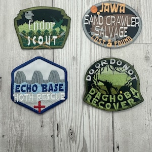 May include: Four embroidered patches featuring Star Wars themes. The patches are green, black, blue, and gray with white text. The text on the patches reads "Endor Scout", "Echo Base Hoth Rescue", "Jawa Sand Crawler Salvage Lost & Found", and "Do or Do Not Dagobah Recovery".
