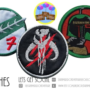 May include: Three embroidered patches featuring Star Wars characters. The first patch is green and white with a red blood drop and a red number 7. The second patch is black with a red and white Mandalorian symbol. The third patch is red with a green Boba Fett helmet.