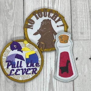 May include: Three embroidered patches featuring a brown bird with the text "No Touchy!" a purple and blue figure with the text "Pull the Lever" and a red bottle with a black llama inside.