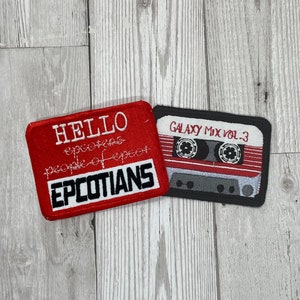 May include: Two embroidered patches. One is red with white text that says "HELLO EPCOTIANS, people of EPCOT". The other is a black and red cassette tape with the text "GALAXY MIX VOL. 3".