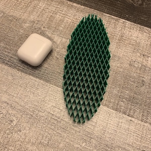 May include: A white rectangular case and a green plastic grid-like object on a wood surface.