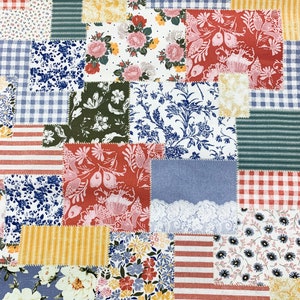 May include: A patchwork fabric featuring a variety of patterns and colors. Squares of floral, striped, and gingham fabrics are stitched together. Colors include red, blue, yellow, green, and white. The fabric is likely used for quilting or crafting projects.