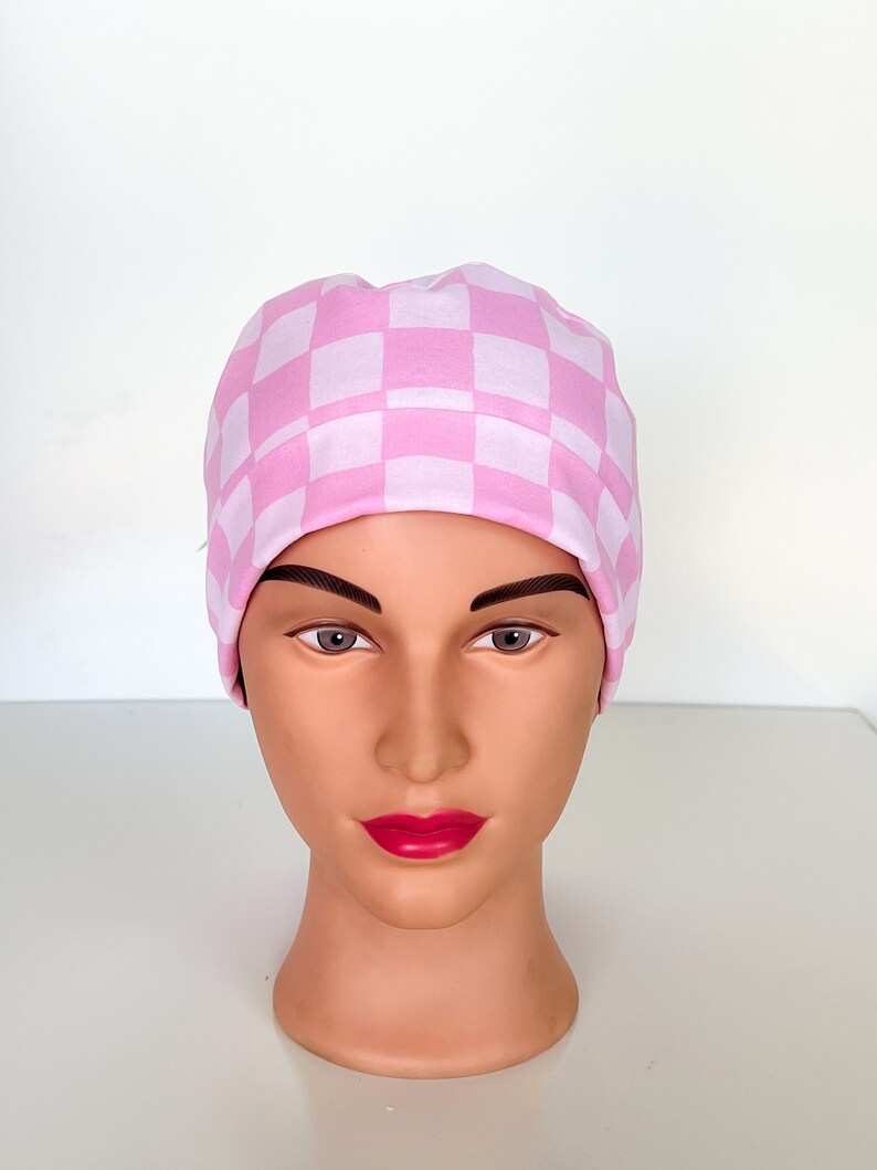 May include: A pink and white checkered scrub hat. The hat is made of a soft, comfortable fabric and is perfect for nurses, doctors, and other healthcare professionals.
