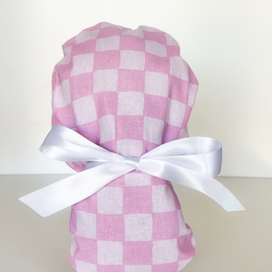 May include: Pink and white checkered scrub hat with a white satin ribbon tied in a bow.