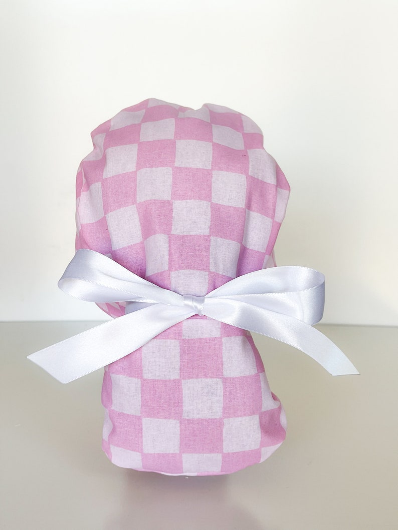 May include: Pink and white checkered scrub hat with a white satin ribbon tied in a bow.