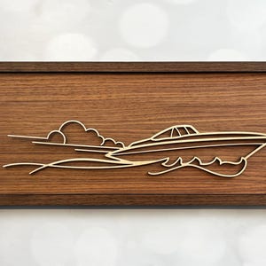 May include: A wooden wall art piece with a cutout design of a boat speeding through the water with a cloud in the background.