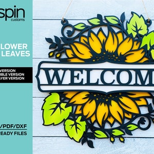 May include: A laser cut wooden welcome sign with a sunflower and leaves design. The sign is in black, yellow, and green. The text "WELCOME" is in white letters on a black background.