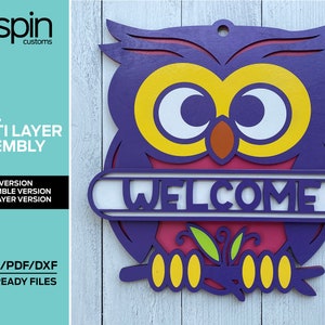 May include: A multi-layered wooden owl cutout with a welcome sign. The owl is purple, yellow, and orange. The sign is pink with white lettering. The owl is holding a branch with green leaves.