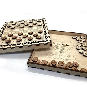 May include: A wooden game board with a checkerboard pattern and heart-shaped pieces. The board is open to reveal a set of wooden tokens with phrases like "Give Good Luck" and "Talk Dirty". The game is called "Lover's Checkers" and the rules are printed on the board.