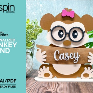 May include: Personalized wooden monkey stand with glasses and a pink bow. The stand has a wooden sign that says "Casey".