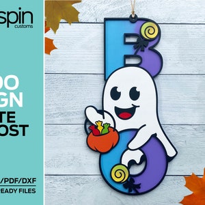 May include: A wooden Halloween sign with a cute ghost holding a bucket of candy. The sign is painted in shades of blue, purple, and white. The letters "BOO" are cut out of the sign and the ghost is holding a bucket of candy with a pumpkin design. The sign is perfect for decorating your home for Halloween.