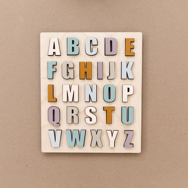 May include: A wooden alphabet puzzle with letters A through Z in various pastel colors, including light blue, light purple, light pink, and orange.