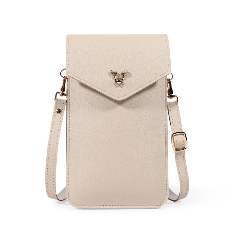 May include: A beige leather crossbody phone bag with a gold deer charm. The bag has a flap closure and a long adjustable strap.