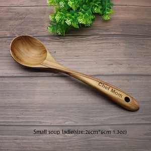 Op de afbeelding: Een houten soeplepel met een bruine afwerking en een handvat met de tekst "Chef Mom". De lepel is 26 cm lang en 6 cm breed en weegt 1,3 oz. Kleine soeplepel (maat: 26 cm * 6 cm 1,3 oz)