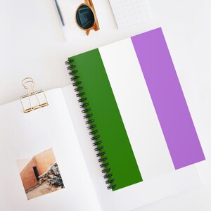 May include: A spiral bound notebook with a green, white, and purple striped cover.