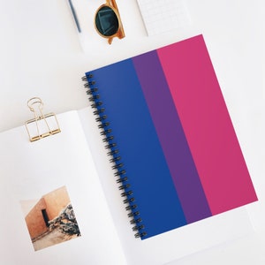 May include: A spiral bound notebook with a bi-colored cover. The cover is divided into three sections: blue, purple, and pink. The notebook is perfect for taking notes, journaling, or sketching.