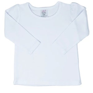 Puede incluir: Camiseta blanca de manga larga con cuello redondo. La camiseta tiene una peque&ntilde;a etiqueta con el texto "AJ Brands 12M" en la parte delantera.
