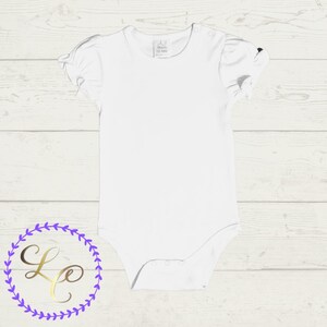 Puede incluir: Un body blanco para beb&eacute; con mangas cortas y un borde con volantes. El body tiene una peque&ntilde;a etiqueta con el texto "A.7 Mundo 12-18M" en la parte delantera.