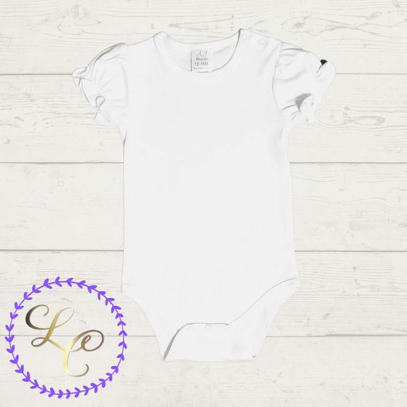 Puede incluir: Un body blanco para beb&eacute; con mangas cortas y un borde con volantes. El body tiene una peque&ntilde;a etiqueta con el texto "A.7 Mundo 12-18M" en la parte delantera.