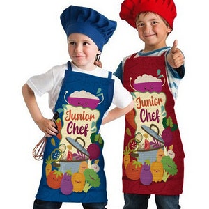 May include: Two children wearing chef hats and aprons with a cartoon design of vegetables and a pot. The aprons say "Junior Chef" in a banner. One apron is blue and the other is red.