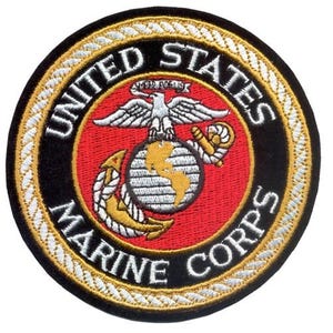 Puede incluir: Parche bordado circular con el emblema del Cuerpo de Marines de los Estados Unidos. El parche tiene un fondo negro con texto blanco que dice "UNITED STATES MARINE CORPS". El emblema central incluye un águila, un globo terráqueo y un ancla, con detalles en rojo y dorado.