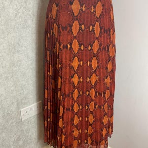 May include: A white ceramic mug with a black handle and the text "But First, Coffee" in a bold, black font. The mug is set against a blurred background, suggesting a cosy setting.